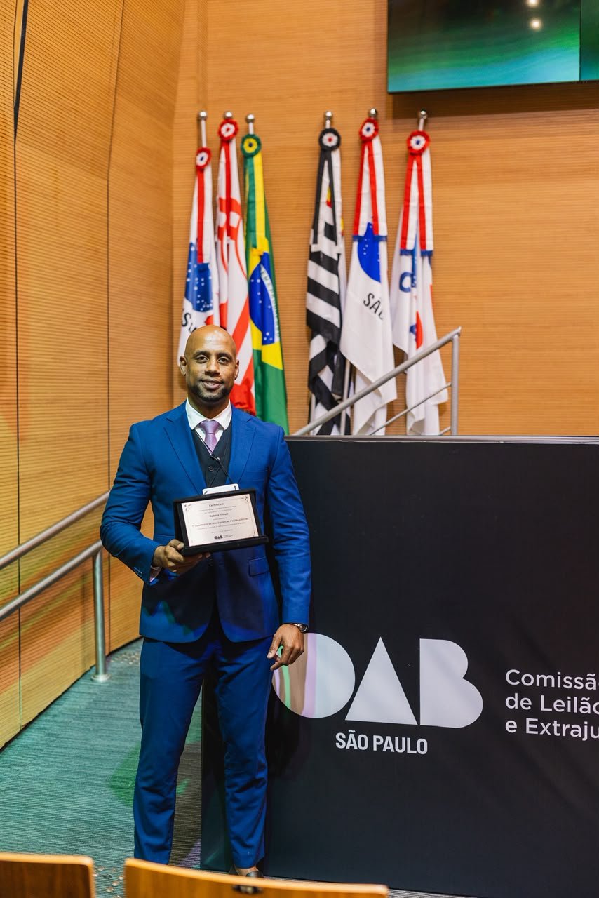 Dr. Rubens Filippe de Jesus segurando o certificado do 1º Congresso de Leilão Judicial e Extrajudicial, no auditório da OAB São Paulo